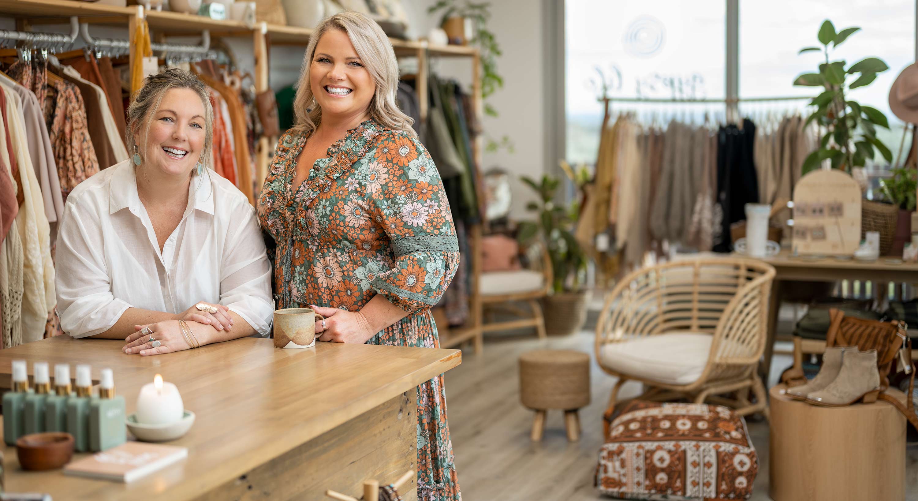 Two women in a clothes shop smiling at camera